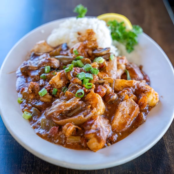Bayou City Seafood & Pasta's shrimp étouffée with rice, garnished with green onions and a lemon wedge.